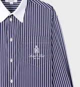 Camisa celeste claro a rayas verticales con cuello y puños blancos, corte oversized y bolsillo en el pecho con logo bordado.