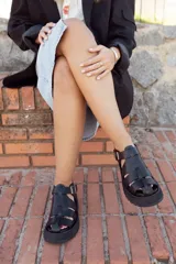 Sandalias negras de cuero con plataforma y tiras anchas entrecruzadas.