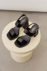 Sandalias de cuero negro con plataforma delantera, taco ancho y tira ajustable en el talón.