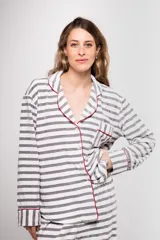 Pijama de tela tipo velvet a rayas horizontales grises y blancas, con vivos en color rojo. Incluye camisa de manga larga con botones frontales y bolsillo en el pecho, y pantalón recto con elástico en la cintura.