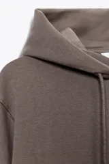 Sudadera de manga larga con capucha ajustable mediante cordones, bolsillo frontal tipo canguro y puños y ruedo en tejido rib.