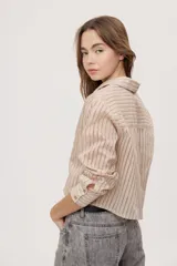 Camisa de manga larga con diseño de rayas verticales en tonos celestes, blancos y marrones, confeccionada en tejido semitransparente con cuello camisero y cierre frontal de botones.