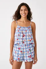 Conjunto de pijama de dos piezas confeccionado en tejido ligero con estampado de cuadros vichy en tonos celestes y blancos, complementado con un diseño de fresas y cerezas. El top es de tirantes finos con escote fruncido elástico, y el short cuenta con cintura elástica cómoda.