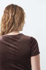 Top de manga corta confeccionado en terciopelo negro, con textura acanalada y acabado con leve brillo. Presenta un diseño ajustado al cuerpo con cuello redondo.