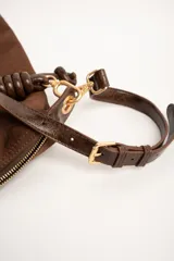 Cartera tipo shopper color marrón, con solapa frontal decorativa en tono más oscuro y tiras con nudos. Incluye herrajes dorados y un charm colgante con cuentas de madera.