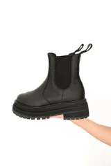 Botas Chelsea negras de cuero vacuno con elásticos laterales, caña media y suela track.