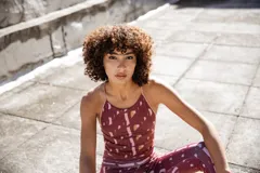 Top deportivo color borgoña con estampado abstracto en tonos rosa y beige, con tirantes finos y espalda deportiva.