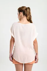 Blusa color blanco de corte holgado, con mangas cortas y detalle de botones en el lateral.