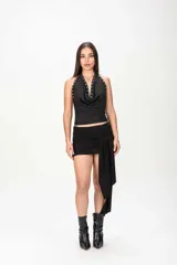 Top halter negro con escote drapeado y tirantes decorados con ojales metálicos.