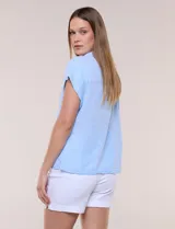 Camisa de lino de estructura recta, color beige con rayas verticales blancas. Cuenta con cuello solapa, escote en V abierto, abotonadura frontal, bolsillo plaqué en el pecho, mangas cortas de hombro caído y ruedo recto.