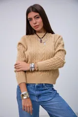 Sweater de punto color beige con cuello redondo, mangas largas y detalles de trenzas en el frente y las mangas.
