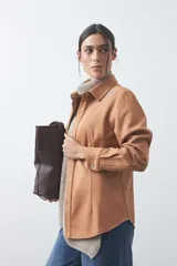 Sobrecamisa de gamuza color marrón con bordados decorativos estilo western en la zona de los hombros y cierre frontal con botones metálicos.