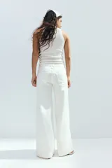 Jean de cinco bolsillos en denim rígido, de color blanco, con piernas amplias, corte holgado y cintura estándar con cierre y botón.