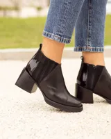 Botín Chelsea de cuero negro, con elástico lateral acanalado y detalle de cuero charol en el talón. Posee punta cuadrada y taco ancho y bajo.