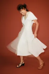Vestido midi de color blanco, con escote en V y mangas cortas abullonadas.
