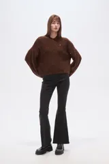 Polera de punto color marrón con destellos brillantes, cuello redondo, mangas largas abullonadas y diseño holgado.