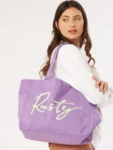 Bolso tipo tote bag de tela liviana color lila con el logo "Rusty" estampado en verde claro.