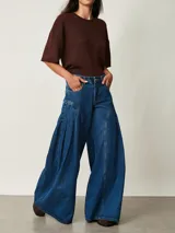 Jean de denim azul de tiro medio, con diseño wide leg de corte muy amplio y pinzas laterales decorativas que aportan volumen.