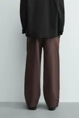 Pantalón jogger de algodón color marrón oscuro, de corte relajado y pierna ancha. Presenta cintura elástica con cordón ajustable y bolsillos laterales y uno trasero de plastrón.