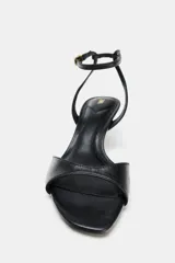 Sandalia de piel color negro, con tira delantera, cierre de hebilla en la pulsera del tobillo, tacón medio fino y acabado en punta.
