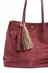 Charm para bolso compuesto por flecos de cuero sintético color marrón, decorados con pequeñas tachas metálicas doradas. Incluye un aro y un cierre de mosquetón metálico en tono dorado.