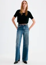 Jeans de tiro medio con diseño de pernera recta y ancha, de color azul con efecto desgastado.