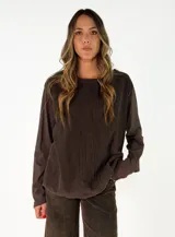 Blusa de manga larga color marrón oscuro, con cuello redondo y detalle de costuras verticales en el frente.
