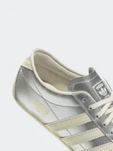 Zapatillas Adidas Tokyo color plateado con las tres tiras laterales en color crema.