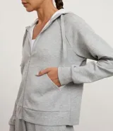 Campera deportiva con capucha ajustable, cierre frontal por cremallera, mangas largas con sisa raglán y puños ajustados. Presenta bolsillo tipo canguro y cordones con lettering estampado.