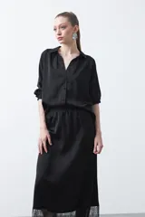 Falda midi negra de caída fluida con cintura elastizada y un amplio detalle de encaje negro en el bajo.