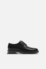 Zapato de vestir tipo derby color negro, de cuero liso, con horma redonda y suela con ligero tacón.