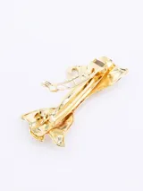 Broche para el pelo dorado con forma de moño.