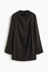 Vestido corto de corte holgado en tejido con textura levemente arrugada. Presenta cuello elevado, pliegues en un hombro que crean un efecto drapeado frontal, mangas largas con puños rectos y cierre oculto en la espalda.