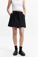Falda corta de color negro, confeccionada en algodón liviano. Presenta una cintura elastizada con lazo ajustable y bolsillos laterales.