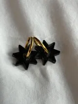 Aros tipo argolla dorada con dije colgante en forma de estrella de acrílico color rosa.