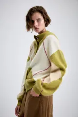 Chaqueta de punto con diseño de rombos en tonos verde oliva y crema, con cuello redondo, cierre frontal de botones y mangas largas con puños ajustados.