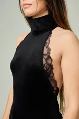Body negro confeccionado en terciopelo acanalado, con cuello alto, diseño sin mangas y detalles de encaje a lo largo de las sisas y los hombros.
