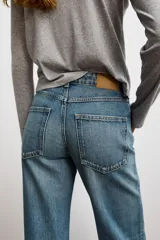 Jeans celeste de tiro alto, corte recto y largo, con cinco bolsillos y cierre frontal con cremallera y botón.