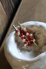 Par de caravanas con base dorada y piedras rojas y perlas.