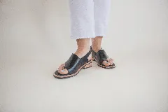 Sandalias de cuero negro con tira entre los dedos, talón descubierto y hebilla lateral.