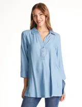 Blusa de lyocell color azul claro, con cuello camisero, escote en V y cierre frontal parcial con botones. Presenta mangas tres cuartos amplias y un corte holgado con aberturas laterales en el ruedo.