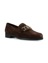 Mocasines de gamuza color marrón, con herraje metálico dorado en el empeine y suela plana con tacón bajo.
