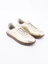 Zapatillas deportivas doradas con suela marrón y cordones al tono.