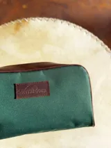 Neceser de lona verde con detalles en cuero color beige y etiqueta con logo de la marca Sierra Mora.