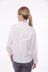 Camisa color blanco con cuello alto con volados y cierre frontal con botones ocultos.