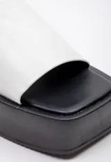 Sandalias negras de plataforma con punta cuadrada y tira ancha sobre el empeine.