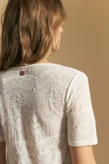 Top de manga corta confeccionado en tejido jacquard con textura en relieve. Presenta escote en V y un diseño frontal con líneas diagonales que crean un efecto cruzado.