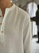 Camisola blanca de lino de manga larga con cuello mao y tira de botones frontal.