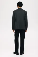 Blazer cruzado de tejido gris oscuro con finas rayas verticales blancas (pinstripe). Presenta solapas de pico, cierre de doble botonadura con botones oscuros, bolsillo superior insertado y dos bolsillos delanteros ribeteados con solapa. Tiene botones decorativos en los puños y abertura trasera.