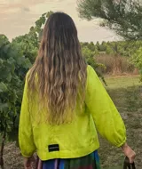 Blusa color verde lima con escote en V, mangas largas abullonadas con puños elásticos y cierre frontal con lazos.